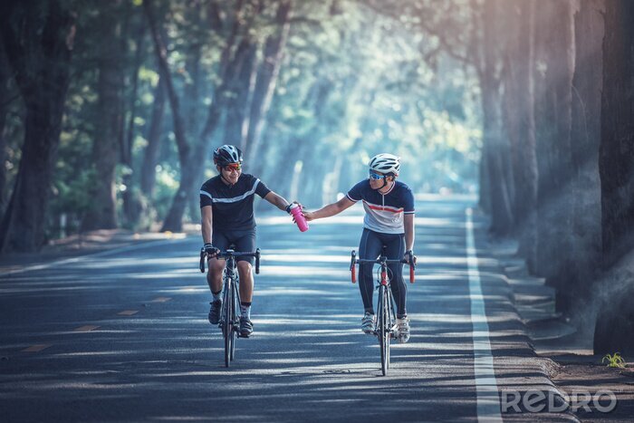 Canvas Asian men are cycling road bike in the morning and share out water to each other