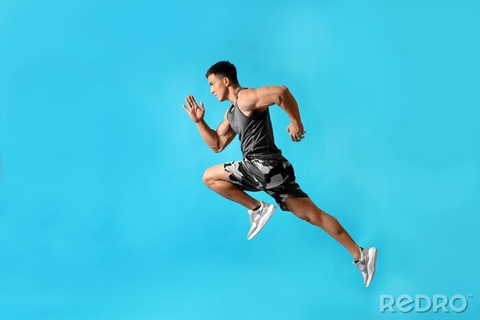 Canvas Athletic young man running on light blue background, side view