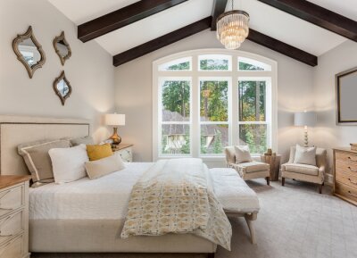 Canvas Beautiful furnished master bedroom interior in luxury home . Features vaulted ceiling with wood beams and chandelier.
