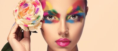 Canvas Beautiful girl model with multi-colored paints on her face. Woman with rose flower and bright color make-up. Cosmetics, beauty and makeup.  Spring and summer flowering  shopping