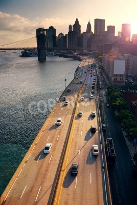 Bezig verkeer in New York City Manhattan met Brooklyn Bridge over de Hudson rivier bij zonsondergang.