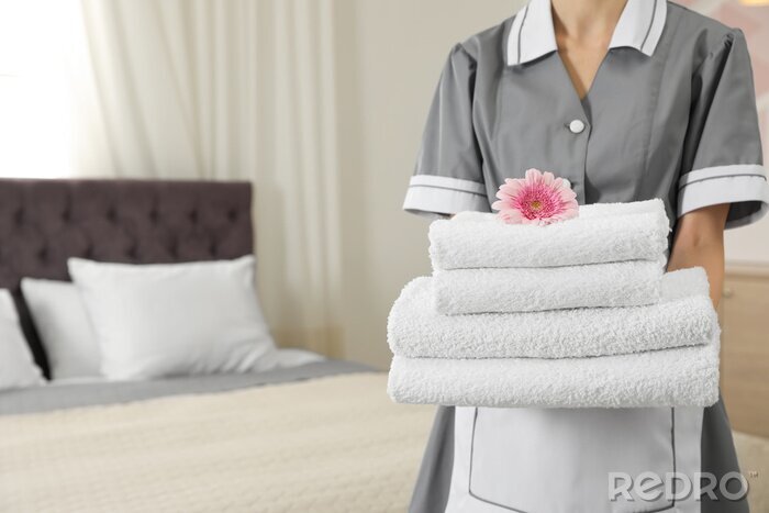 Canvas Chambermaid with stack of fresh towels in hotel room, closeup. Space for text