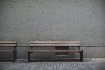 Canvas Closeup shot of wooden benches against a grey stone wall in an empty street