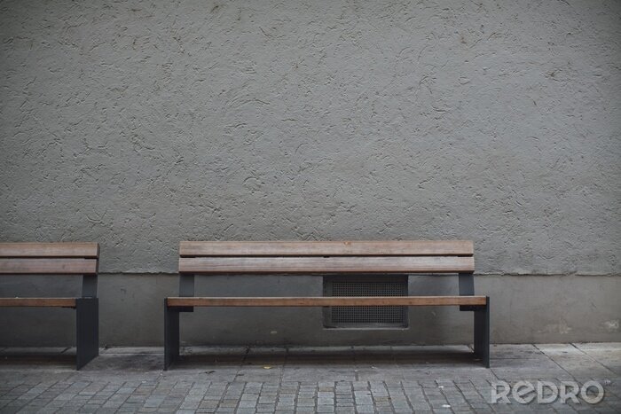 Canvas Closeup shot of wooden benches against a grey stone wall in an empty street
