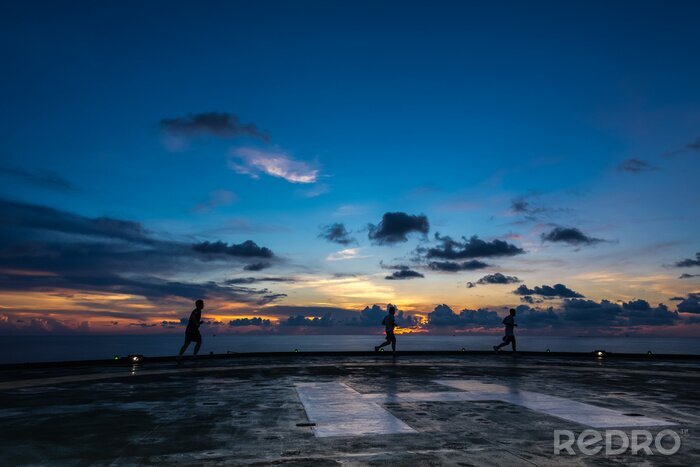 Canvas Drie mannen lopen op booreiland helikopterplatform in zonsondergang tijd