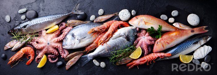 Canvas Fresh fish and seafood assortment on black slate background. Top view.