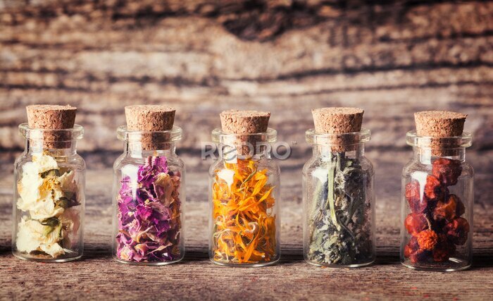 Canvas Glazen flesjes met kruiden op een ruwe houten achtergrond
