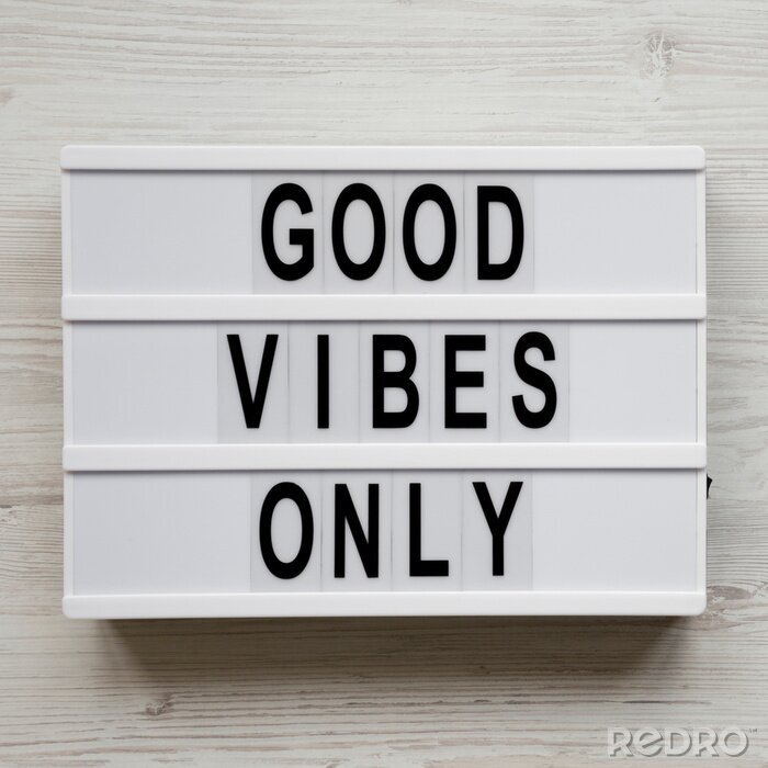 Canvas 'Good vibes only' words on lightbox over white wooden surface, top view. From above, overhead, flat lay. Copy space.