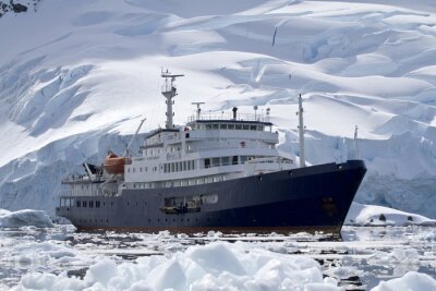 grote blauwe toeristische schip in de Antarctische wateren tegen de achtergrond o