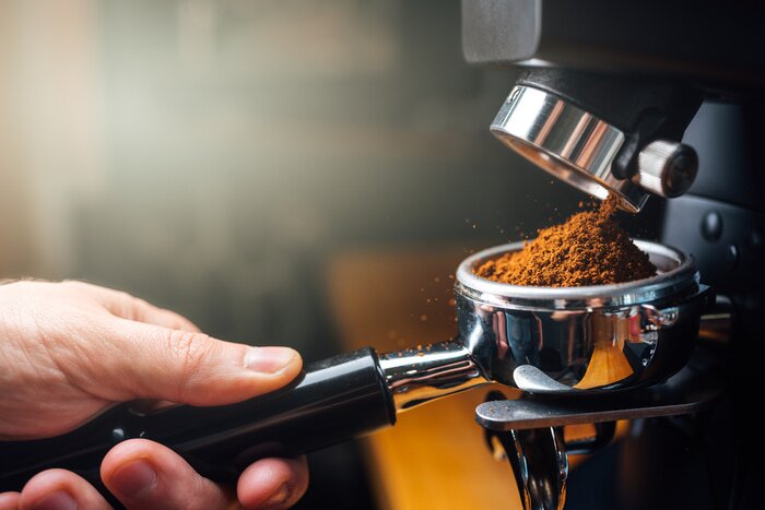 Canvas Ground coffee pouring into a portafilter with a grinder