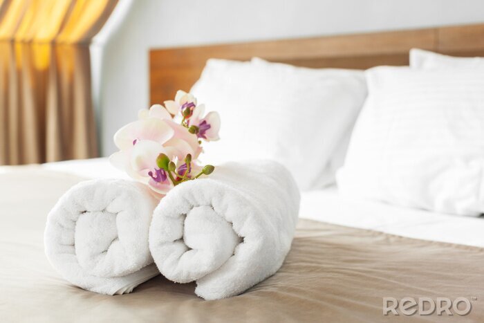 Canvas handdoeken en bloem op bed in hotelkamer