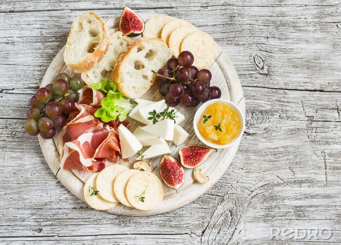 Canvas heerlijk aperitief wijn - ham, kaas, druiven, crackers, vijgen, noten, jam, geserveerd op een lichte houten plank