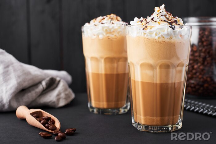 Canvas Iced caramel latte koffie in een hoog glas met chocoladesiroop en slagroom. Donkere houten achtergrond.