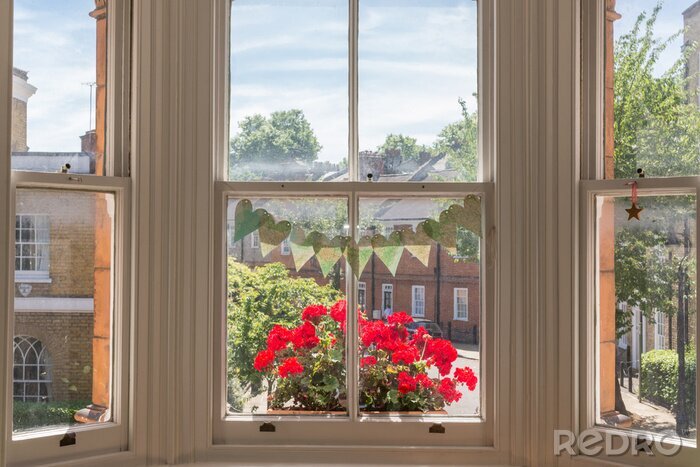Canvas Interieur van een Victoriaans Brits huis met oude houten witte ramen en rode geranium bloemen op de raambank tegen een traditionele Engelse straat