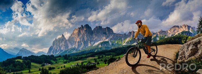 Canvas Man cycling on electric bike, rides mountain trail. Man riding on bike in Dolomites mountains landscape. Cycling e-mtb enduro trail track. Outdoor sport activity.