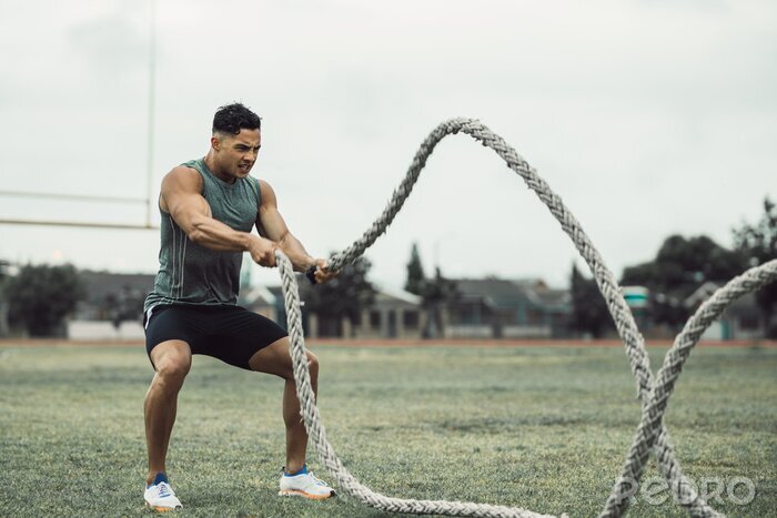 Canvas Man doing workout using battle ropes on the ground