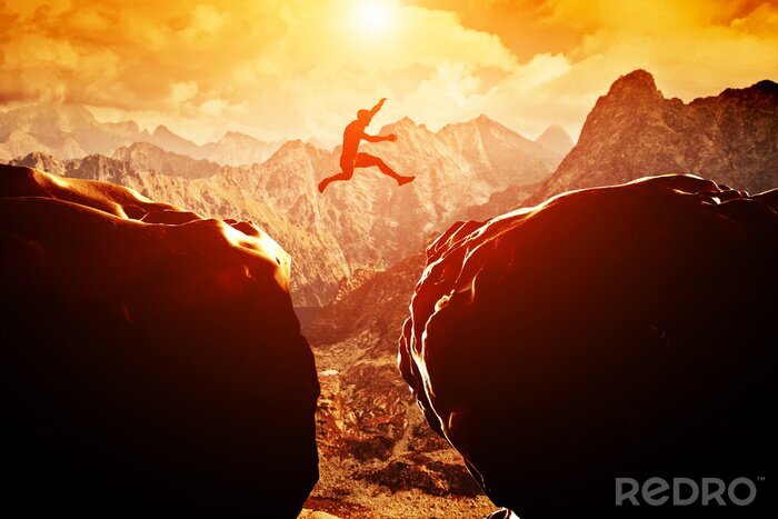Canvas Man springen over de afgrond tussen twee bergen bij zonsondergang