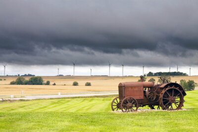 Canvas Oude roestige tractor met storm weer op de achtergrond