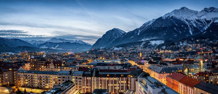 Canvas Panorama der Skyline von Innsbruck, Alpen, Österreich, im Winter am Abend mit schneebedeckten Bergen im Hintergrund