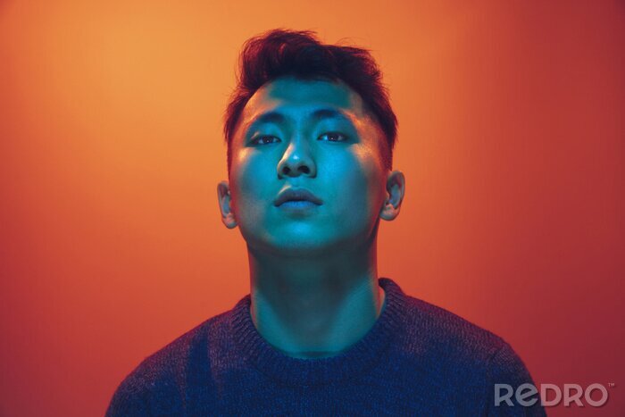 Canvas Portrait of a guy with colorful neon light on gradient studio background. Male model with calm and serious mood. Facial expression, cyberpunk, millenials lifestyle and look like. Future, technologies.