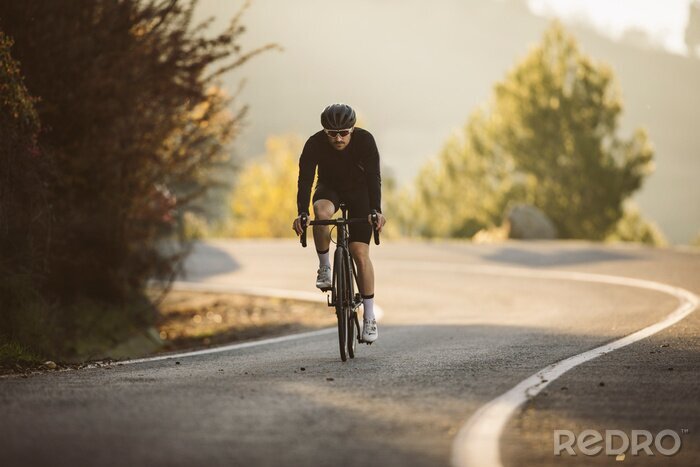 Canvas Professional road bicycle racer in action. Men cycling mountain road bike at sunset.