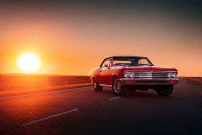 Canvas Retro rode auto staande op asfalt weg bij zonsondergang