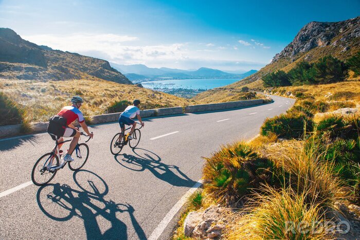 Canvas Road cycling photo. Two triathlete train in beautiful nature. Sea and mountains in background. Alcudia, Mallorca, Spain