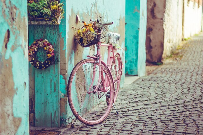 Canvas Roze vintage fiets met mand vol bloemen naast een oud cyaan gebouw in Spanje
