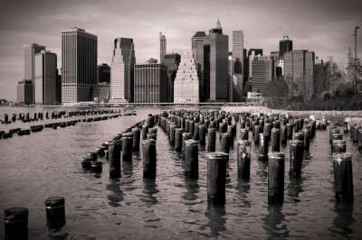 Skyline von Manhattan mit Holzpfählen im Wasser, Schwarzweiß