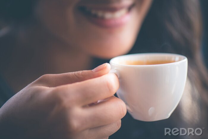 Canvas Smiling woman holing hot espresso coffee on hand at cafe in the morning