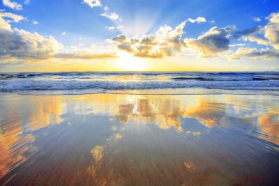 Canvas Spectaculaire gouden zonsopgang boven zee met een strand in voorgrond