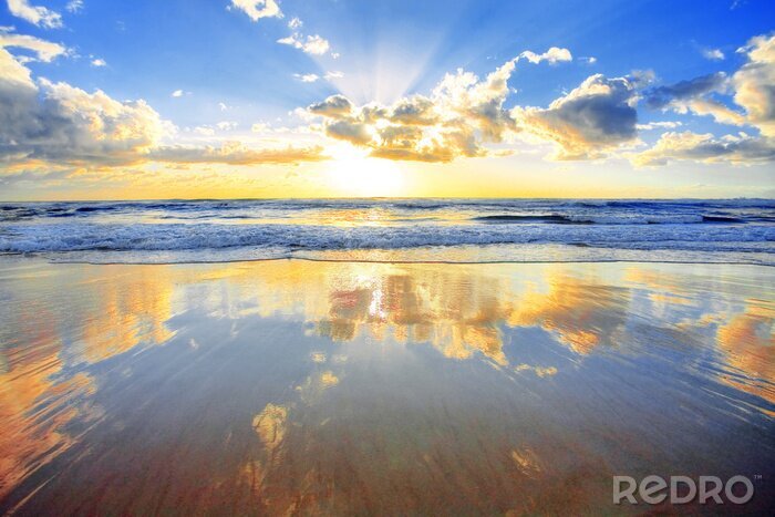 Canvas Spectaculaire gouden zonsopgang boven zee met een strand in voorgrond