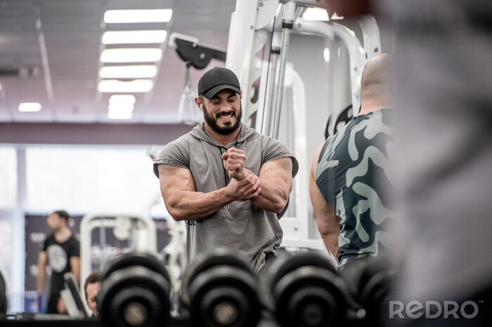 Canvas strong muscle bearded caucasian athlete man holding his wrist with hand during sport training injury with grimace of pain on his face indoor gym