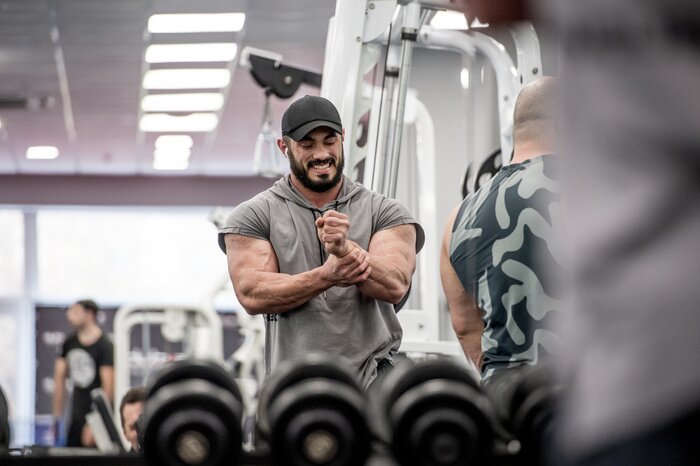 Canvas Strong muscle bearded caucasian athlete man holding his wrist with hand during sport training injury with grimace of pain on his face indoor gym