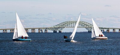 Three two person sailboats in front of the Great South Bay bridge on a windy December afternoon