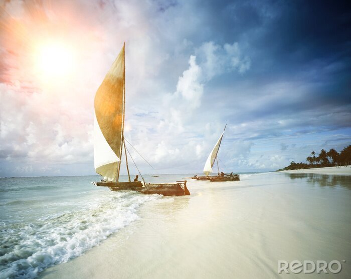 Canvas Two sail boats on a beach with sea and the sun