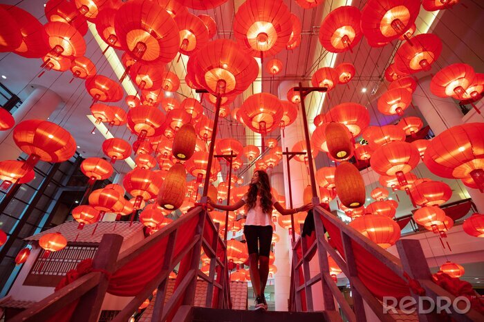 Canvas Woman walking and enjoying traditional red lanterns decorated for Chinese new year Chunjie. Asian culture inspiration. Trend lava color.