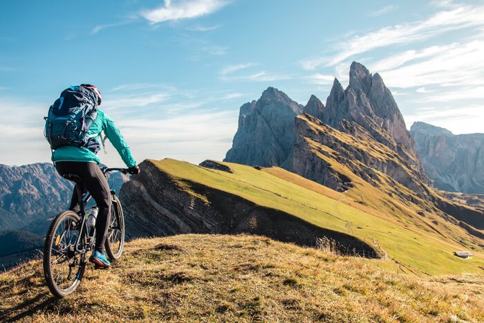 Canvas Young man with mountain bike cycling on Seceda mountain peak at sunrise. Puez Odle, Trentino, Dolomites, Italy.