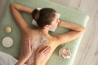 Canvas Young woman having body scrubbing procedure with sea salt in spa salon, top view