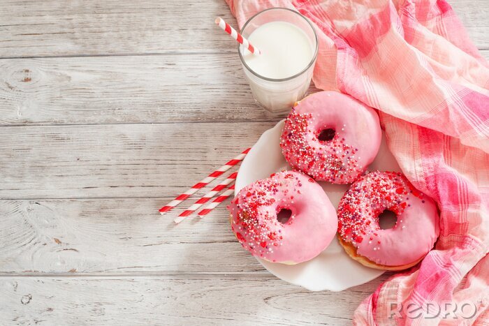 Canvas zoete donuts met aardbeien en kersen roze suikerglazuur en melk op een houten achtergrond