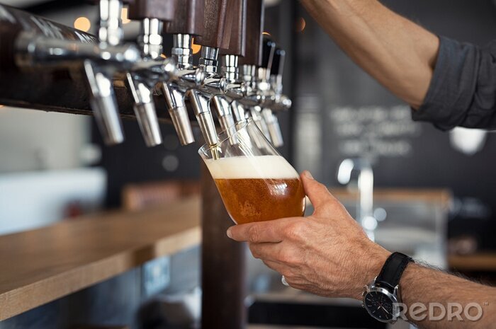 Fotobehang Barman schenkt bier uit een schenkfles