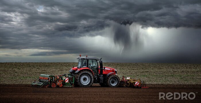 Fotobehang beautiful landscape with a farmer plowing his fields before the storm