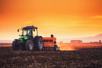Fotobehang Beautiful sunset, farmer in tractor preparing land with seedbed cultivator