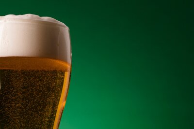 Fotobehang Bier met schuim op een groene achtergrond