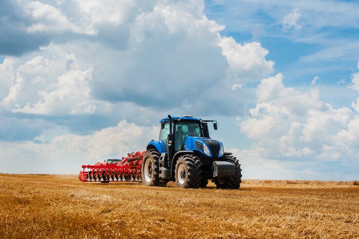 Fotobehang Blue tractor in the field, agricultural machinery work, field and beautiful sky