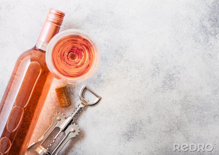 Fotobehang Bottle and glasses of pink rose wine with cork and corkscrew opener on stone kitchen table background. Top view. Space for text