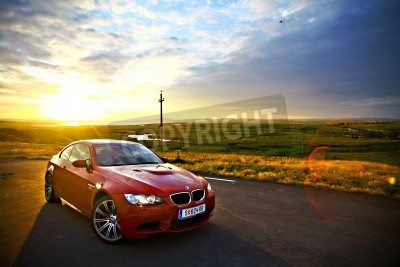 Fotobehang Bucharest, Romania - July 3, 2013: A BMW M3 car drives through a beautiful scenery, at sunset. The BMW M3 is a high-performance version of the BMW 3-Series, developed by BMW's motorsport division, BMW