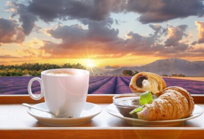 Coffee with croissants against lavender field during colorful sunset in Provence, France
