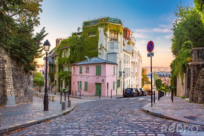 Fotobehang Comfortabele oude straat met roze huis bij de zonnige zonsopgang, kwart Montmartre in Parijs, Frankrijk