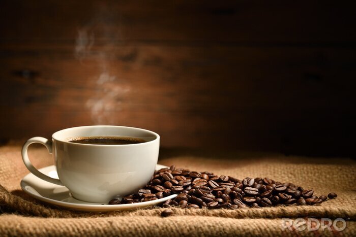 Fotobehang Cup of coffee with smoke and coffee beans on burlap sack on old wooden background